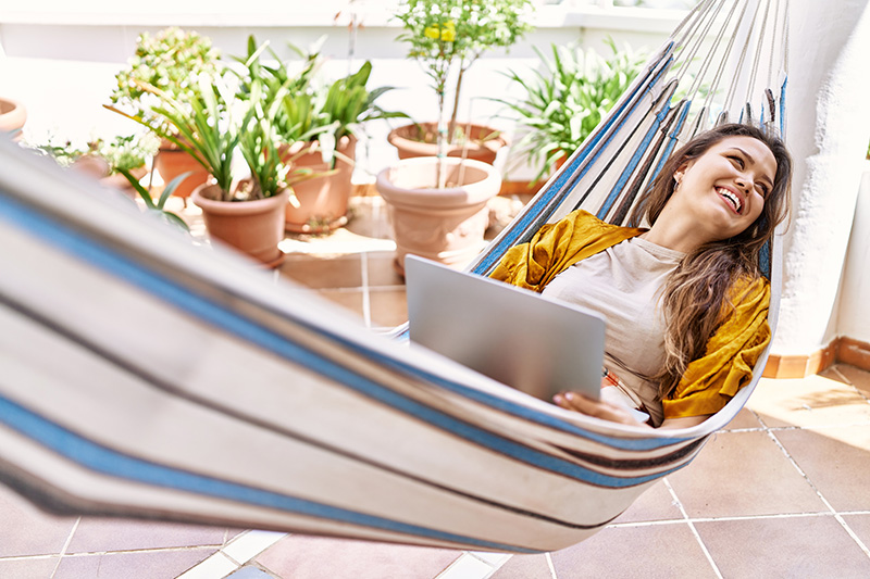 young,hispanic,girl,using,laptop,lying,on,hammock,at,the